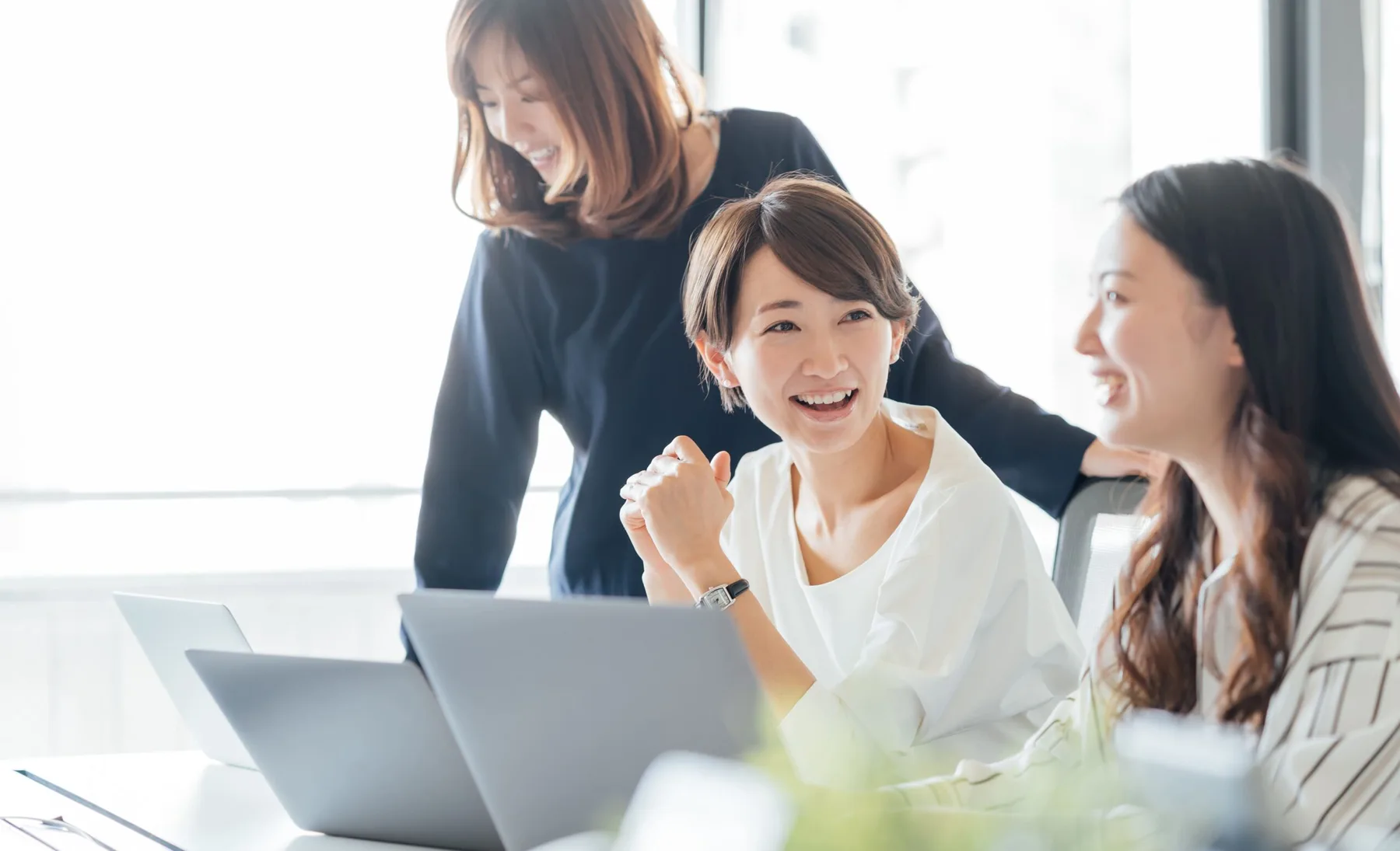 パソコンを囲んで相談するスタッフのイメージ